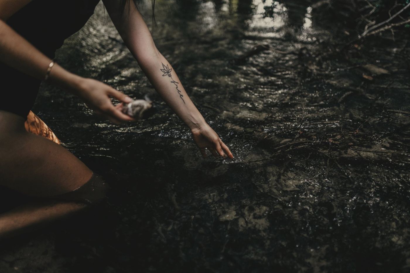 Sarahs Hand berührt das Wasser eines Bachs