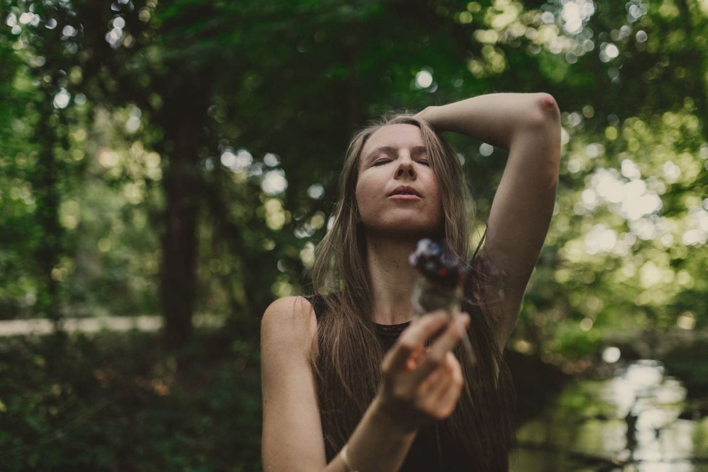 Sarah mit geschlossenen Augen und Räucherwerk am Bach
